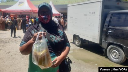 Ibu Dinem (59) memperlihatkan minyak goreng yang dibeli di pasar murah yang diselenggarakan oleh Dinas Perindustrian dan Perdagangan Provinsi Sulawesi Tengah. Selasa (15/3/2022) (Foto: VOA/Yoanes Litha)