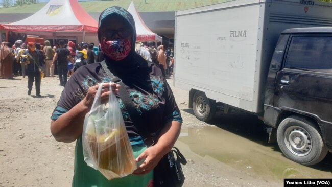 Ibu Dinem (59) memperlihatkan minyak goreng yang dibeli di pasar murah yang diselenggarakan oleh Dinas Perindustrian dan Perdagangan Provinsi Sulawesi Tengah. Selasa (15/3/2022) (Foto: VOA/Yoanes Litha)