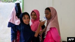 রোহিঙ্গা শরণার্থীরা আচেহ প্রদেশের বিরুয়েনে নৌকায় করে তাদের আগমনের পর একটি মসজিদের প্রাঙ্গনে তাকিয়ে আছে। ৬ই মার্চ, ২০২২। 