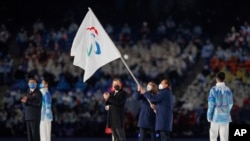 The Vice Mayor of Milan and the Mayor of Cortina d'Ampezzo wave the Paralympic flag during the Flag Handover Ceremony during the closing ceremony at the Beijing National Stadium Beijing 2022 Winter Paralympic Games in Beijing, China, March 13, 2022.