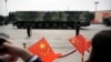 Para penonton mengibarkan bendera China ketika kendaraan militer yang membawa rudal balistik DF-41 bergerak dalam parade militer di Beijing pada 1 Oktober 2019. (Foto: AP/Mark Schiefelbein)