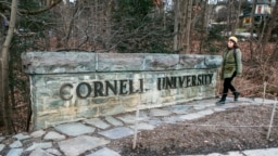 A woman walks by a Cornell University sign on the Ivy League school's campus in Ithaca, New York, Jan. 14, 2022. 