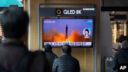 People watch a TV screen showing a news program reporting about North Korea's missile with file footage, at a train station in Seoul, South Korea, Wednesday, March 16, 2022. 