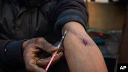 FILE - A young man injects himself with Nyaope (a form of black tar heroin, possibly mixed with other substances) in downtown Johannesburg, June 26, 2021. 