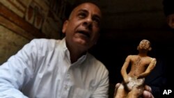 Mostafa Waziri, secretary general of the Supreme Council of Antiquities, displays a statue found in a recently discovered tomb near the famed Step Pyramid, in Saqqara, south of Cairo, Egypt, March 19, 2022.