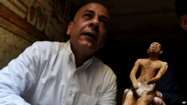 Mostafa Waziri, secretary general of the Supreme Council of Antiquities, displays a statue found in a recently discovered tomb near the famed Step Pyramid, in Saqqara, south of Cairo, Egypt, March 19, 2022.