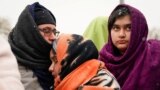 FILE - Members of an Afghan family, who once fled the war in Afghanistan, wait to board a bus bound for a refugee center, after fleeing the Russian invasion in Ukraine, in Medyka, Poland, Feb. 28, 2022.