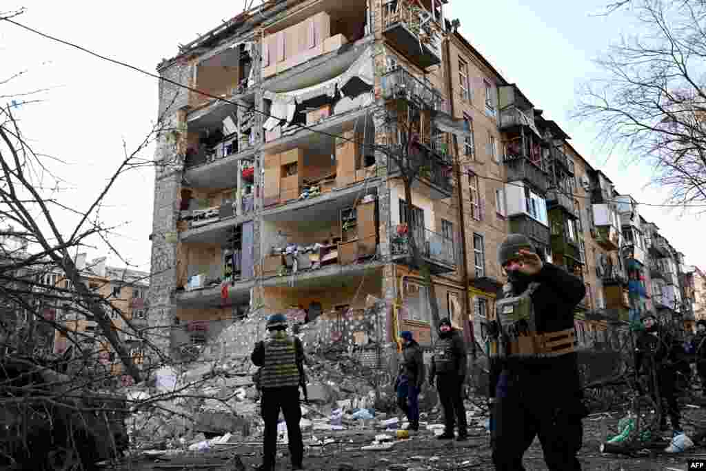 Ukrainian policemen secure the area by a five-storey residential building that partially collapsed after a shelling in Kyiv.