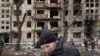 یک مرد بیرون از محوطه یک آپارتمان در کی‌یف که در حملات توپخانه‌ای روسیه تخریب شده است.