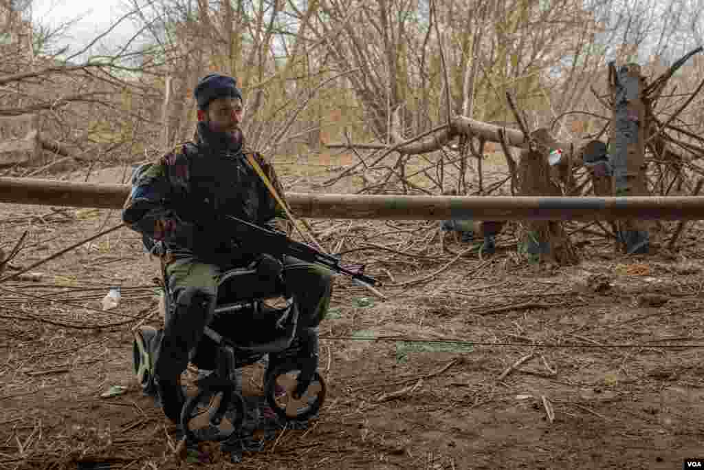 A soldier keeps guard while sitting on a baby stroller left behind by fleeing civilians, in Irpin, Ukraine, March 13, 2022. 