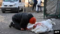 烏克蘭首都基輔一市民跪在俄軍轟炸公寓樓而死亡的一具屍體旁。（2022年3月17日）