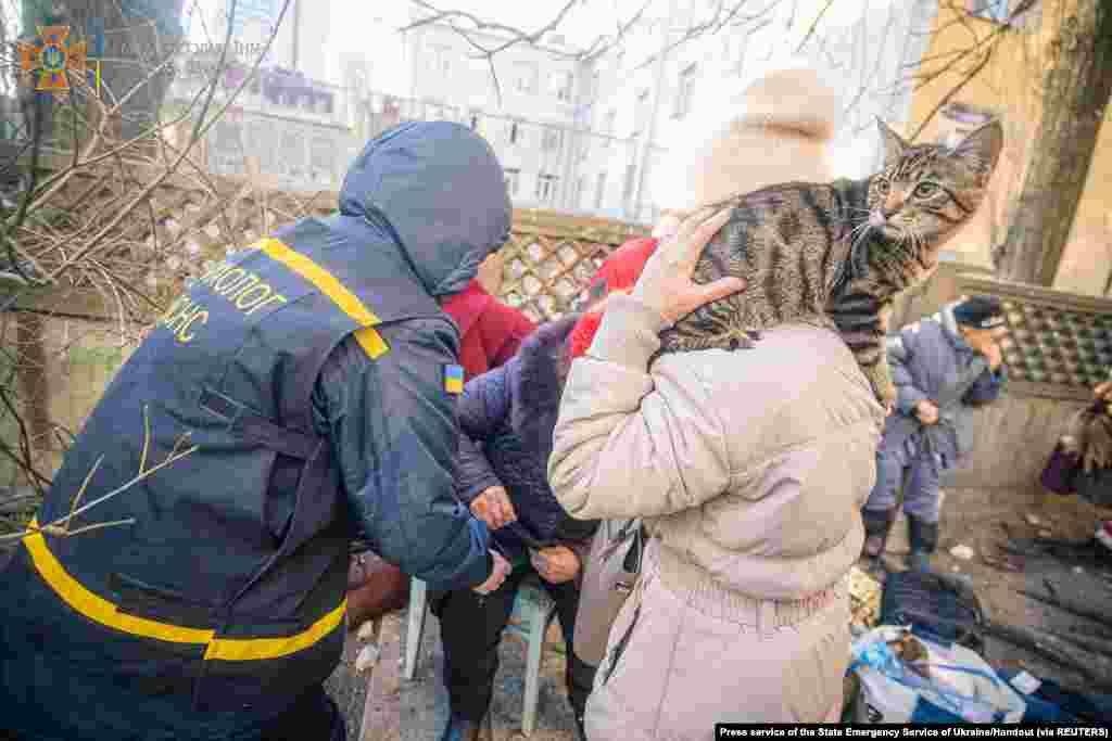 A psychologist helps people evacuated from a residential building damaged by shelling in Kyiv, in this handout picture released March 16, 2022.