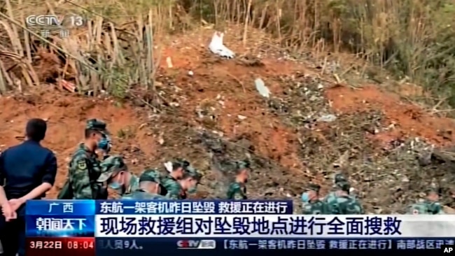 En esta imagen tomada de un video del CCTV de China, soldados registran el lugar donde se estrelló un avión en el condado de Tengxian, en la región autónoma de la etnia zhuang de Guangxi, en el sur de China, el martes 22 de marzo de 2022.