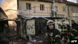 Firefighters extinguish a fire on a house on the 17th day of the Russian invasion of Ukraine after shelling in Kyiv, March 12, 2022.