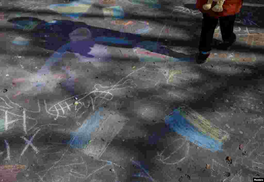 Un niño pasa junto a dibujos con tiza que muestran la bandera ucraniana en un centro para refugiados en Beregsurany.