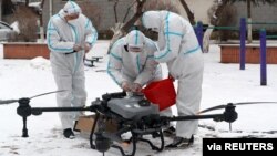 Workers in protective suits prepare a drone amid the snow to disinfect a residential compound under lockdown, following the coronavirus disease (COVID-19) outbreak in Changchun, Jilin province, China, March 14, 2022. (China Daily via Reuters)