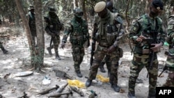 FILE - Members of the Senegalese Armed Forces walk past discarded rockets at a recently captured Movement of Democratic Forces of Casamance (MFDC) rebel base in Blaze Forest, Feb. 9, 2021. 