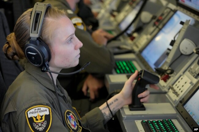 US sailor Riley Junge from Ohio looks at videos of Chinese structures and buildings on board a US P-8A Poseidon plane flying at the Spratlys islands in the South China Sea on March 20, 2022. (AP Photo/Aaron Favila)