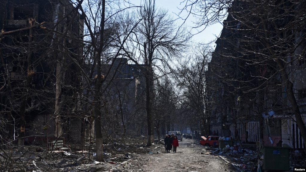 乌克兰马里乌波尔市居民走过被炮火摧毁的居民建筑（2022年3月18日）(photo:VOA)