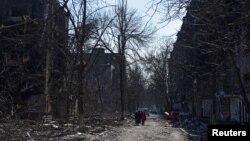 乌克兰马里乌波尔市居民走过被炮火摧毁的居民建筑（2022年3月18日）
