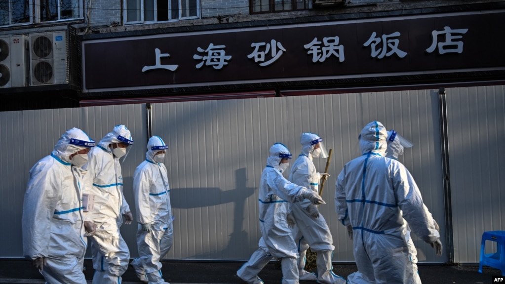 身穿防护服的防疫人员在上海一处因发现新冠疫情而被封闭的小区的屏障外。（2022年3月15日）