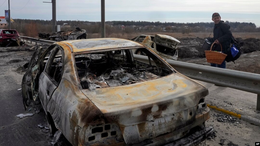 A resident passes by cars burnt in the Russian shellfire as he flees from his hometown Irpin on the road toward the capital Kyiv, Ukraine, March 12, 2022.