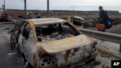 A resident passes by cars burnt in the Russian shellfire as he flees from his hometown Irpin on the road toward the capital Kyiv, Ukraine, March 12, 2022.