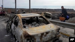 A resident passes by cars burnt in the Russian shellfire as he flees from his hometown Irpin on the road toward the capital Kyiv, Ukraine, March 12, 2022.