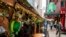 FILE - Pedestrians pass outside the sparsely populated sidewalk dining area beside the Playwright Celtic Pub on Saint Patrick's Day in midtown Manhattan, March 17, 2021, New York.
