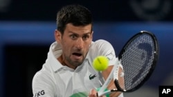 FILE - Serbia's Novak Djokovic returns the ball to Italy's Lorenzo Musetti during a match of the Dubai Duty Free Tennis Championship in Dubai, United Arab Emirates, Feb. 21, 2022.