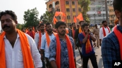 India's Hindu right wing Bajrang Dal activists donning saffron scarves and waving saffron flags demand a probe in the recent killing of one of their associates in Karnataka's Shivamogga district, during a protest rally in Udupi, Karnataka, India, Feb. 23,