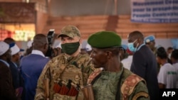 Un agent de sécurité privé du groupe russe Wagner (G) se tient à côté d'un soldat centrafricain lors d'un rassemblement du parti politique Mouvement des Cœurs Unis (MCU) au stade Omnisport de Bangui le 18 mars 2022. (Photo de Barbara DEBOUT /AFP)