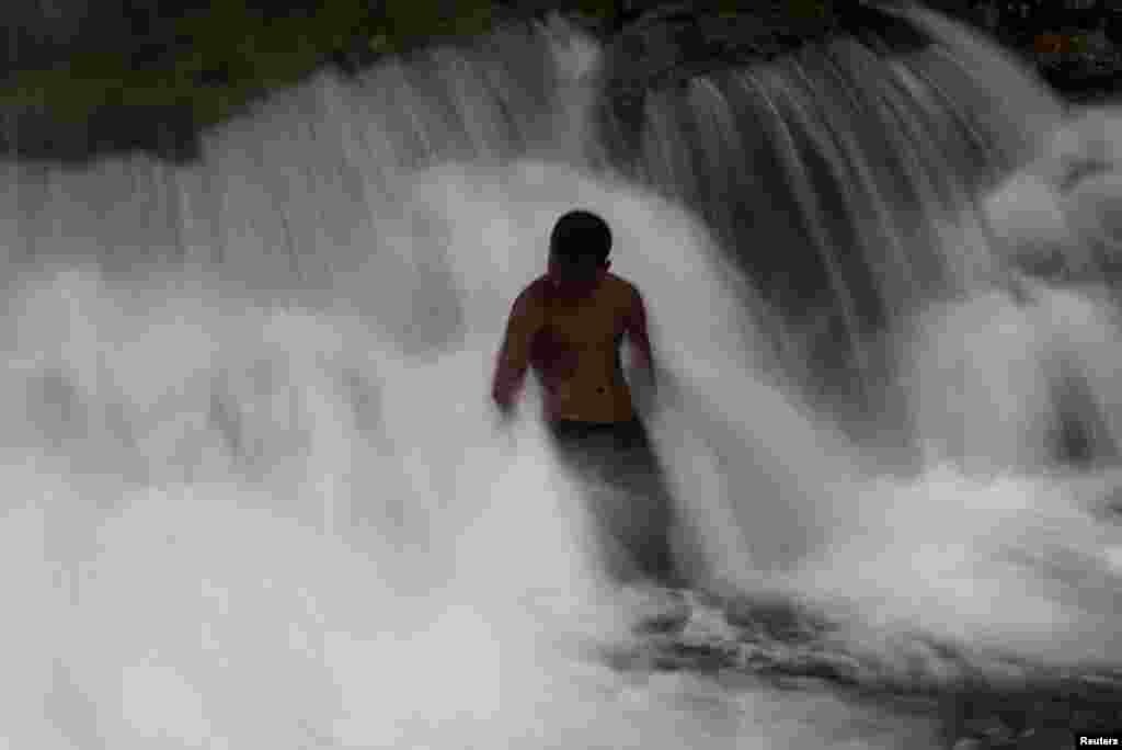 A teenager stands under the waterfall in Pertak, Hulu Selangor, Malaysia.