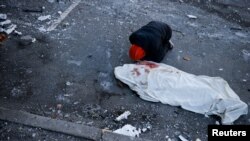 A man mourns next to the body of his mother, who was killed when an intercepted missile hit a residential building, following Russia's invasion of Ukraine, in Kyiv, Ukraine March 17, 2022.