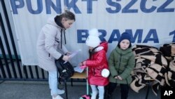 A Ukrainian woman with children looks at paperwork outside a special application point at the National Stadium in Warsaw, Poland, March 19, 2022.