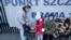 FILE - A Ukrainian woman with children looks at paperwork outside a special application point at the National Stadium in Warsaw, Poland, March 19, 2022. 