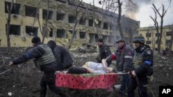 Regu penyelamat dam sukarelawan mengangkat seorang perempuan yang terluka dari rumah sakit bersalin yang hancur di Mariupol, Ukraina, 9 Maret 2022. (AP Photo/Evgeniy Maloletka)