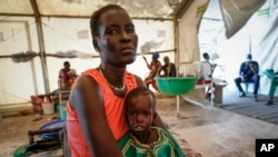 FILE - Nyayiar Kuol holds her severely malnourished 1-year-old daughter, Chuoder Wal, in a hospital run by Medicines Sans Frontieres (Doctors Without Borders) in Old Fangak in Jonglei state, South Sudan, Dec. 28, 2021.