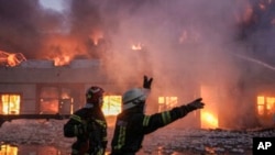 Lực lượng cứu hỏa Ukraine chống chọi với đám cháy tại một nhà kho bị Nga pháo kích ở Kyiv, Ukraine, thứ Năm, ngày 17 tháng 3 năm 2022. (Ảnh AP / Vadim Ghirda)