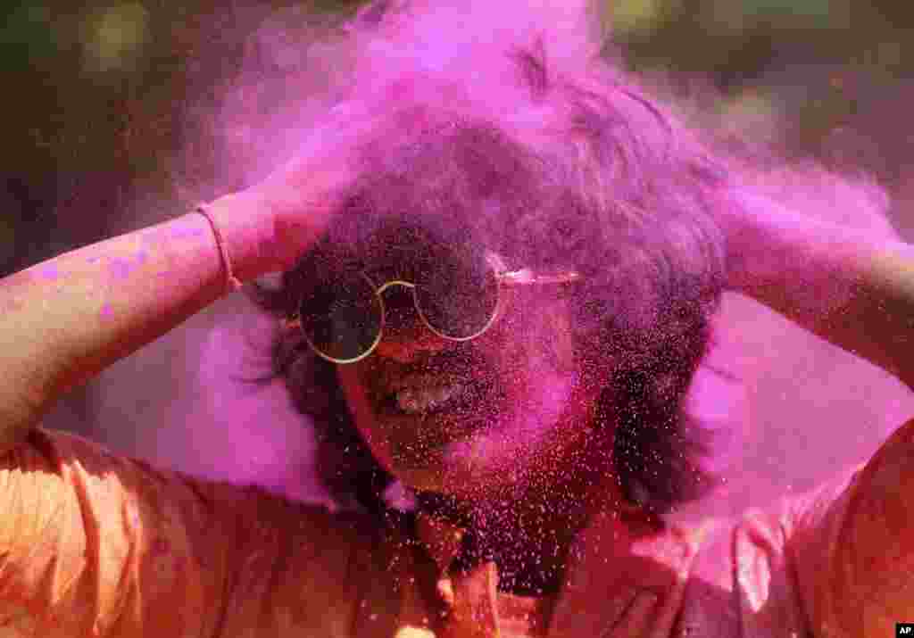 A reveller smeared in colored powder dances during Holi festival in Hyderabad, India.