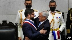 Chile's new President Gabriel Boric, left, is embraced by outgoing President Sebastian Pinera during Boric's swearing-in ceremony at Congress in Valparaiso, Chile, March 11, 2022.