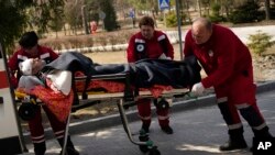 An injured man is wheeled on a stretcher at a local hospital in Novoiavorisk, western Ukraine, March 13, 2022. Local officials in western Ukraine say a Russian airstrike has hit a military training base that has hosted NATO drills.