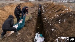 Dead bodies are placed into a mass grave on the outskirts of Mariupol, March 9, 2022, as people cannot bury their dead because of heavy shelling by Russian forces. (AP Photo/Mstyslav Chernov)