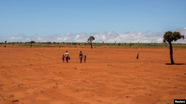 Tarira and her son Avoraza, 4, walk through a field covered with red sand in Anjeky Beanatara, Androy area, Madagascar, February 11, 2022. (REUTERS/Alkis Konstantinidis )
