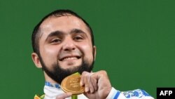 Atlet angkat besi asal Kazakhstan Nijat Rahimov berpose dengan medali emas yang diraihnya setelah ia berhasil menjadi yang terbaik di kelas 77 kilogram pria dalam ajang Olimpiade 2016 di Rio de Janeiro, Brazil, pada 10 Agustus 2016. (Foto: AFP/Goh Chai Hi