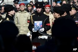 A serviceman carries the photo of Capt. Andrei Paliy, a deputy commander of Russia's Black Sea Fleet, during a farewell ceremony in Sevastopol, Crimea, March 23, 2022. Paliy was killed in action during the fighting with Ukrainian forces in the Sea of Azov port of Mariupol.