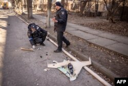 Ukrainian police officers inspect a downed Russian drone in the area of a research institute, part of Ukraine's National Academy of Science, after a strike, in northwestern Kyiv, March 22, 2022.