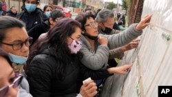 People check a voter list to confirm where they should cast their ballots during legislative elections in Bogota, Colombia, Sunday, March 13, 2022. Colombians went to the polls to renew Congress, and also to choose presidential candidates from three political coalitions whose outcome will be key for the next presidential election on May 29. (AP Photo/Fernando Vergara)