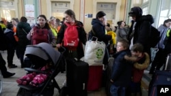 Refugiados con niños esperan un transporte después de huir de la guerra desde la vecina Ucrania en una estación de tren en Przemysl, Polonia, el 22 de marzo de 2022.
