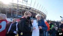 Refugees from Ukraine waiting in line to apply for Polish ID numbers that will entitle them to work, free health care and education. Ukrainian women pack away documents at a special application point at the National Stadium in Warsaw, Poland, 